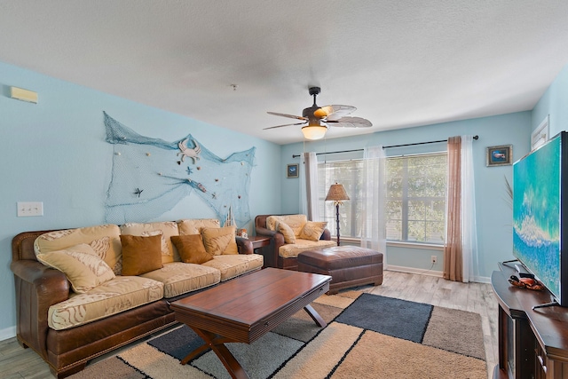 living room featuring ceiling fan, a textured ceiling, and light wood-type flooring