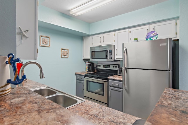 kitchen with gray cabinetry, sink, white cabinetry, and stainless steel appliances