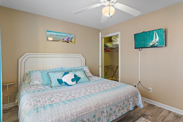 bedroom featuring a closet, hardwood / wood-style flooring, a spacious closet, and ceiling fan