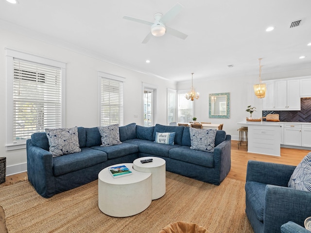 living room with light hardwood / wood-style floors, ceiling fan with notable chandelier, and ornamental molding