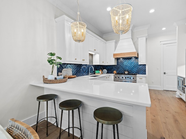 kitchen with kitchen peninsula, white cabinetry, custom range hood, and stainless steel appliances