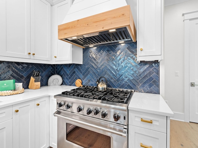 kitchen featuring backsplash, high end stainless steel range, custom range hood, and light wood-type flooring