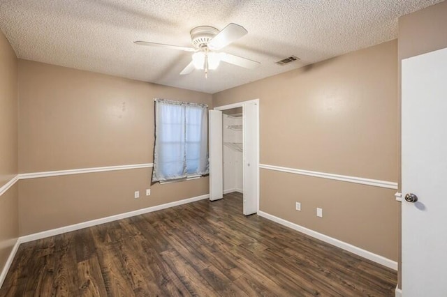 unfurnished bedroom featuring ceiling fan, dark hardwood / wood-style flooring, and a textured ceiling