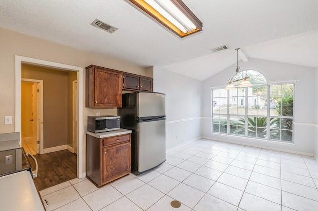 kitchen with decorative light fixtures, lofted ceiling with beams, stainless steel appliances, and light tile patterned floors