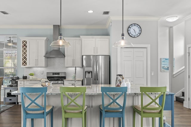 kitchen featuring stainless steel appliances, white cabinetry, a kitchen island with sink, and crown molding