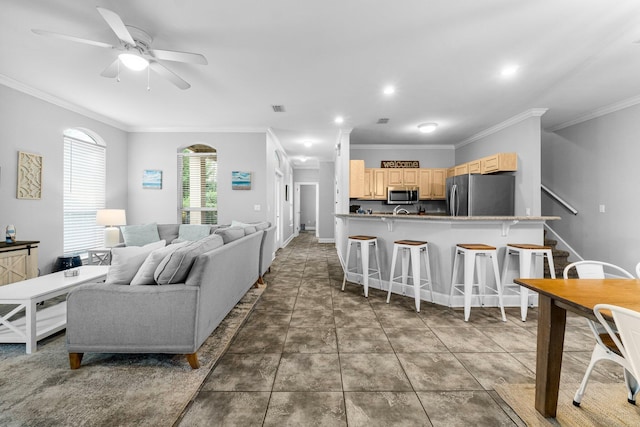 living room with dark tile patterned floors, ceiling fan, and crown molding