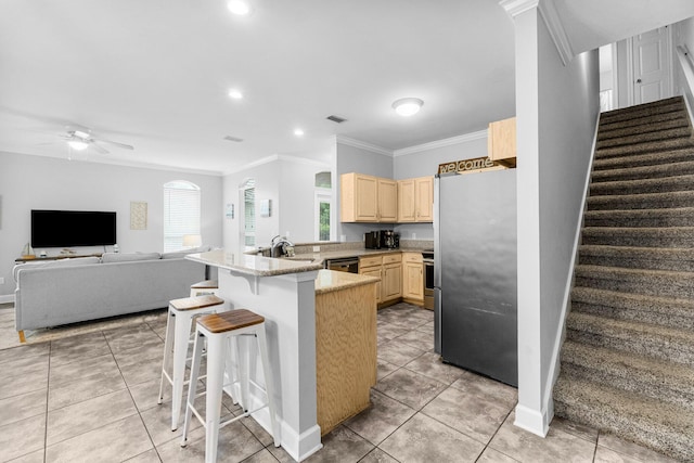 kitchen featuring a kitchen breakfast bar, crown molding, light brown cabinetry, kitchen peninsula, and stainless steel appliances