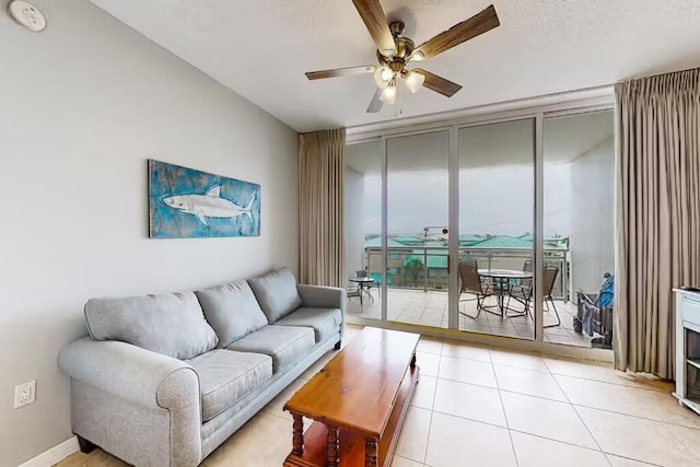 tiled living room featuring ceiling fan and floor to ceiling windows