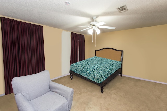 bedroom featuring ceiling fan, light carpet, and a textured ceiling