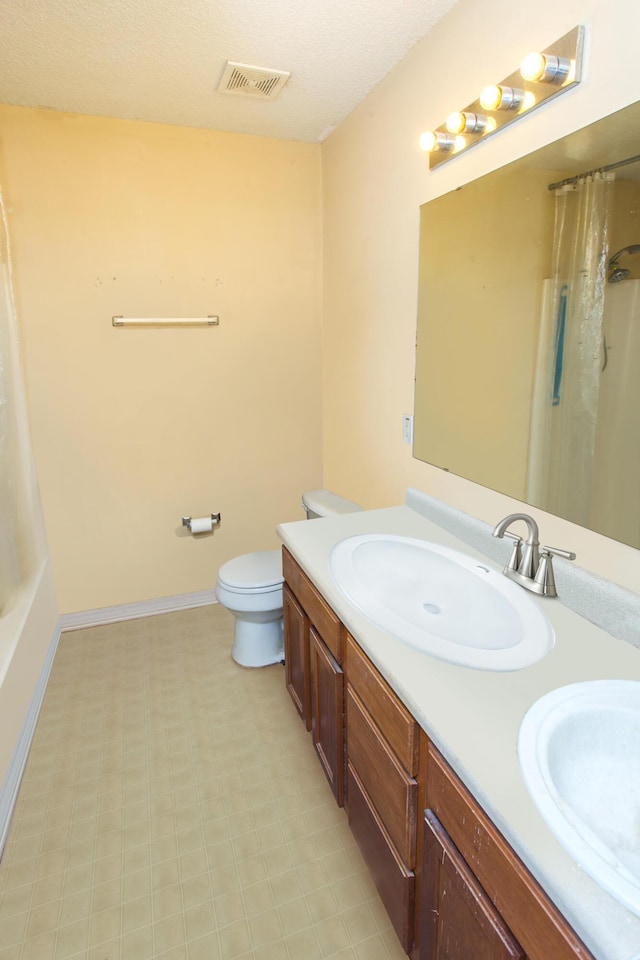 bathroom with a textured ceiling, vanity, and toilet