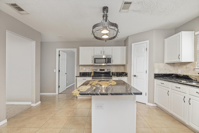 kitchen featuring appliances with stainless steel finishes, a textured ceiling, a kitchen island, and backsplash