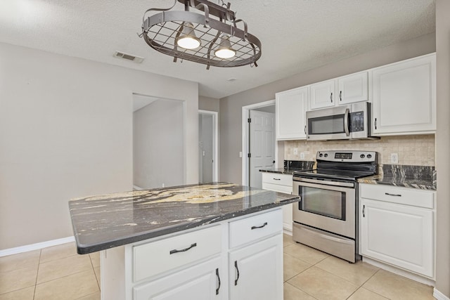 kitchen featuring stainless steel appliances, a kitchen island, dark stone countertops, a textured ceiling, and white cabinets