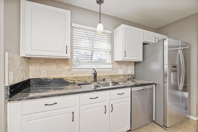 kitchen with sink, hanging light fixtures, dark stone countertops, white cabinets, and appliances with stainless steel finishes