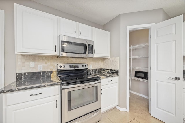 kitchen featuring tasteful backsplash, white cabinetry, stainless steel appliances, and a textured ceiling