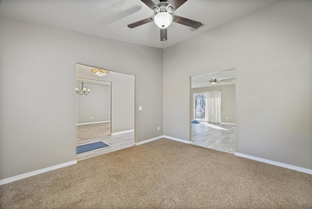 spare room with carpet floors, ceiling fan with notable chandelier, and a textured ceiling