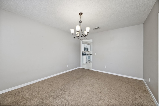 carpeted spare room with a textured ceiling and an inviting chandelier