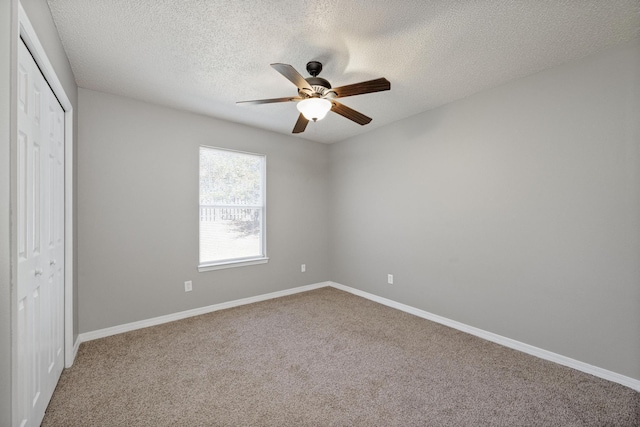 unfurnished bedroom with carpet flooring, ceiling fan, a textured ceiling, and a closet