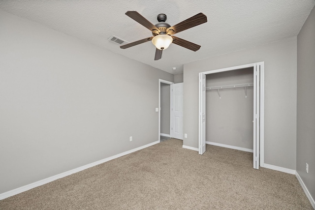 unfurnished bedroom with light carpet, a textured ceiling, a closet, and ceiling fan