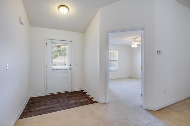 doorway with lofted ceiling, carpet floors, a textured ceiling, and ceiling fan