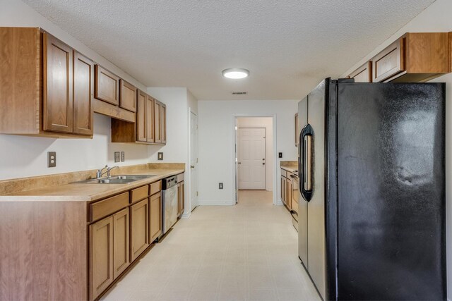 8180 Shooter Ln, Laurel Hill, FL 32567 - kitchen featuring black fridge with ice dispenser, stainless steel dishwasher, light countertops, a sink, and a textured ceiling
