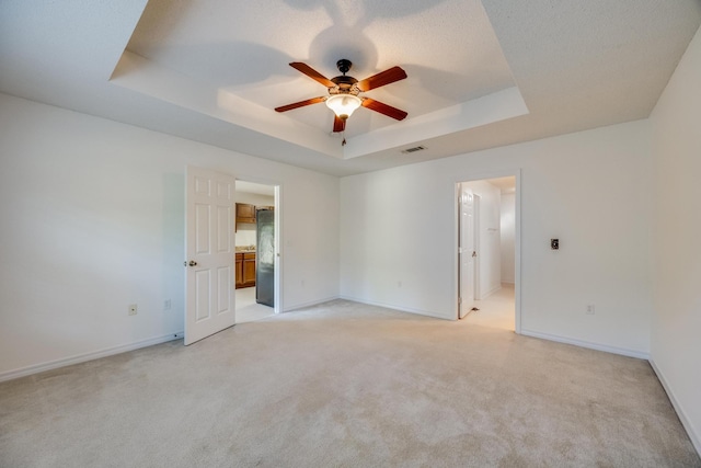 8180 Shooter Ln, Laurel Hill, FL 32567 - spare room with a textured ceiling, a tray ceiling, ceiling fan, and light colored carpet