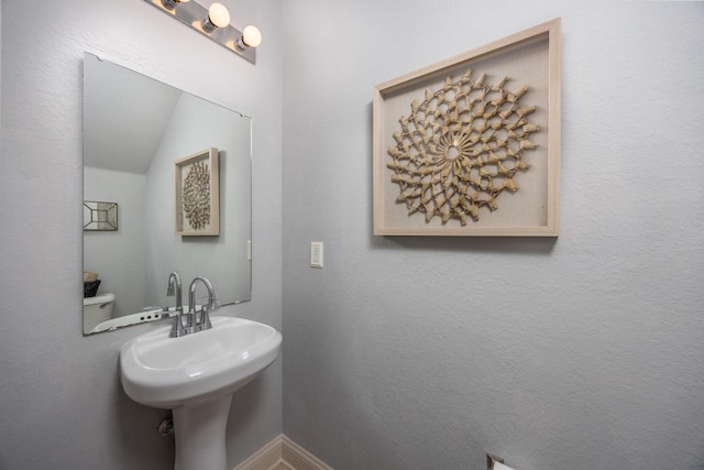 bathroom with toilet, lofted ceiling, and sink