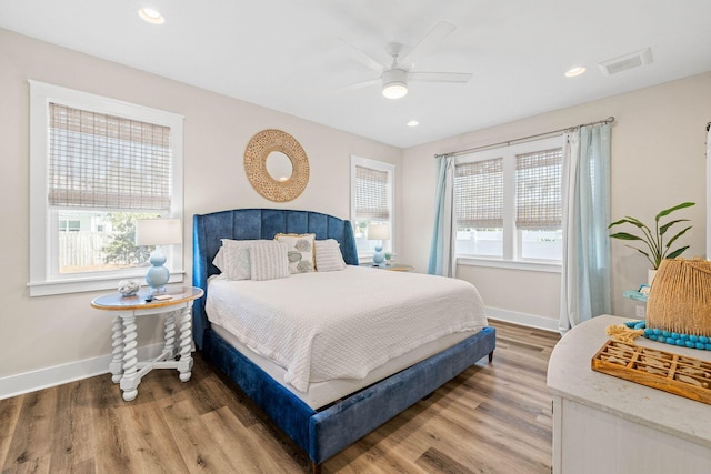 bedroom with multiple windows, ceiling fan, and hardwood / wood-style flooring