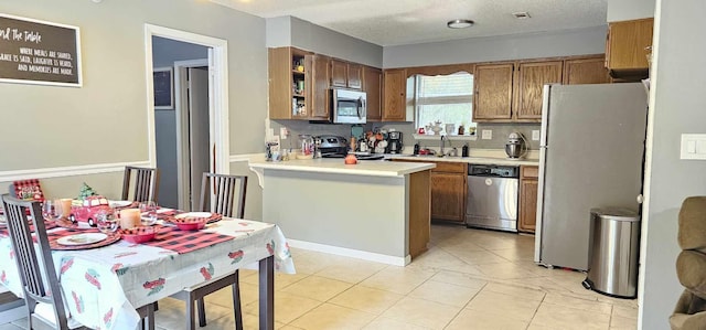 kitchen featuring sink, a textured ceiling, tasteful backsplash, kitchen peninsula, and stainless steel appliances