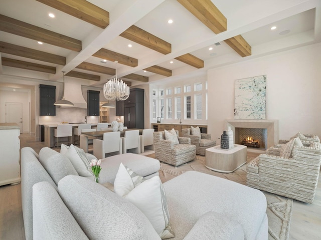 living room with a chandelier, beamed ceiling, light hardwood / wood-style floors, and coffered ceiling