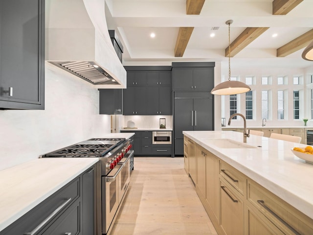 kitchen featuring beam ceiling, light brown cabinets, premium range hood, decorative light fixtures, and high end appliances