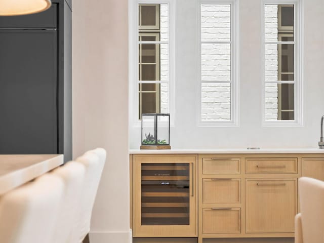 bar featuring light brown cabinetry and beverage cooler