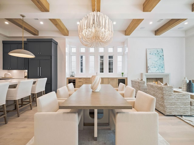 dining space featuring beamed ceiling, light wood-type flooring, and an inviting chandelier