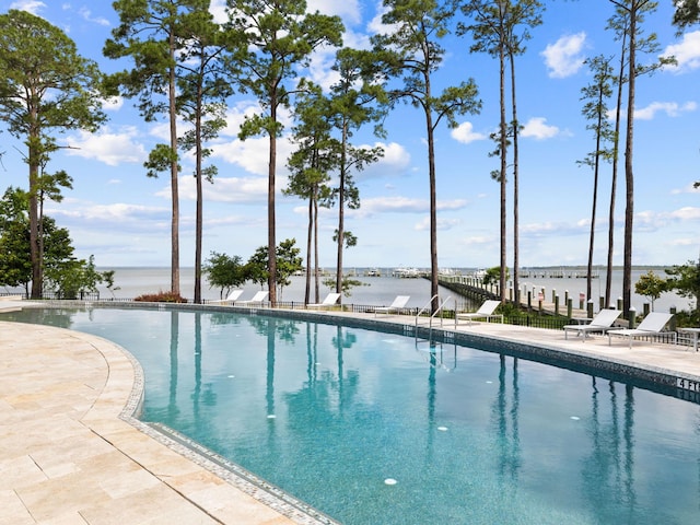 view of swimming pool featuring a water view and a patio