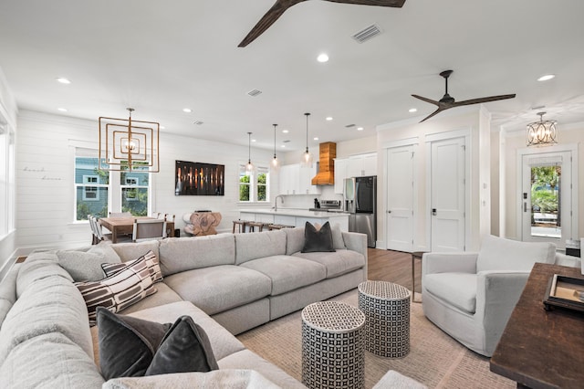 living room featuring ceiling fan, light hardwood / wood-style flooring, and wood walls