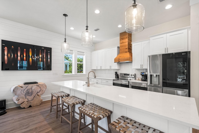 kitchen with stainless steel appliances, dark hardwood / wood-style flooring, premium range hood, decorative light fixtures, and white cabinets