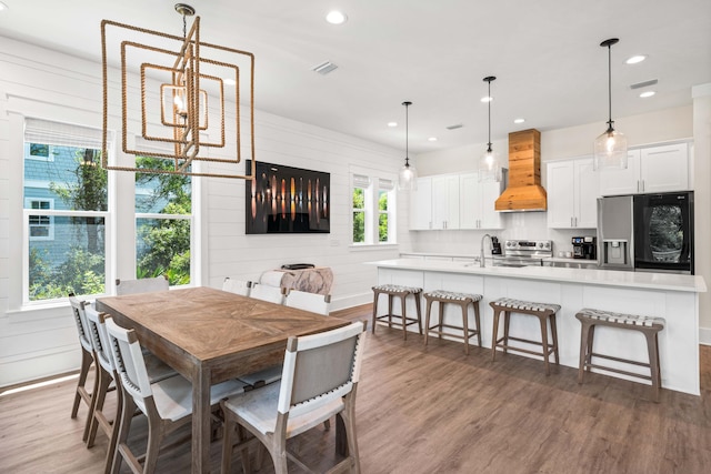 dining area featuring hardwood / wood-style flooring, wood walls, sink, and a chandelier