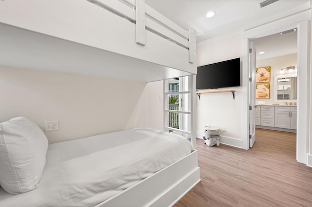 bedroom with light hardwood / wood-style floors and connected bathroom