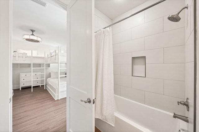 bathroom with hardwood / wood-style floors and shower / bath combo with shower curtain