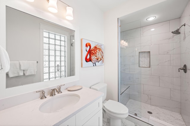 bathroom featuring toilet, a tile shower, and vanity