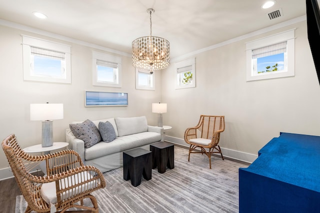 living room with hardwood / wood-style floors, crown molding, and an inviting chandelier