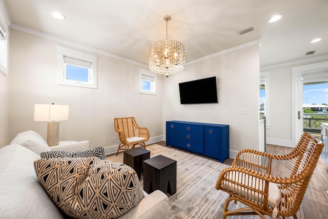 living room with light wood-type flooring, ornamental molding, and an inviting chandelier