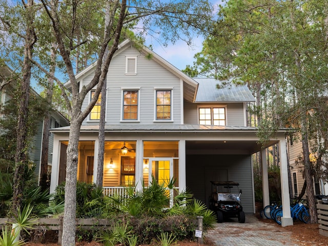 rear view of property with metal roof, a porch, and decorative driveway