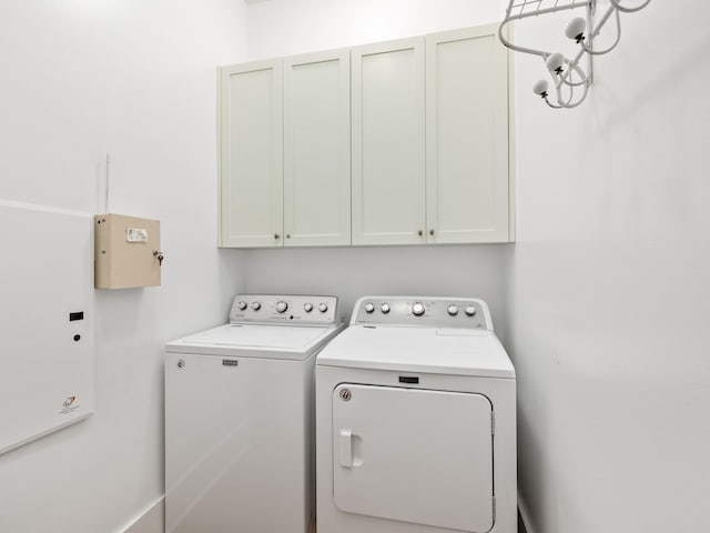 clothes washing area with independent washer and dryer and cabinet space