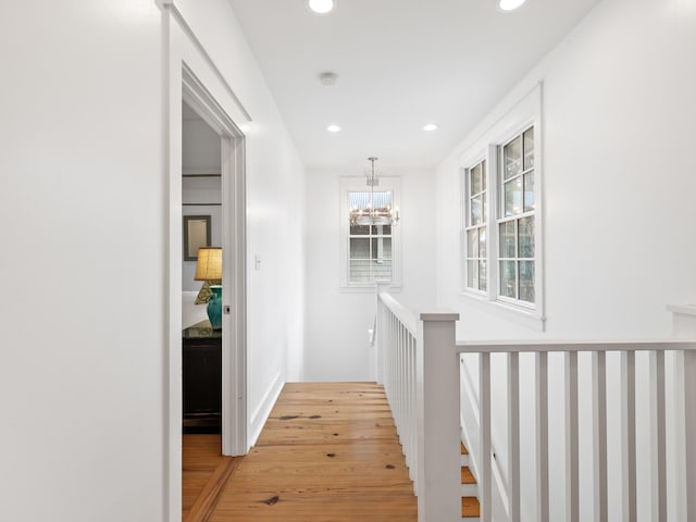 hall with an upstairs landing, recessed lighting, a notable chandelier, and light wood finished floors