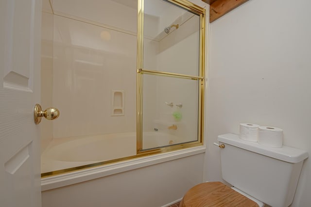 bathroom featuring toilet and bath / shower combo with glass door