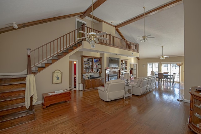 living room featuring hardwood / wood-style floors, high vaulted ceiling, ceiling fan, and beam ceiling