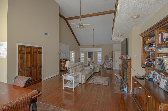 living room with hardwood / wood-style floors, a textured ceiling, high vaulted ceiling, and ceiling fan