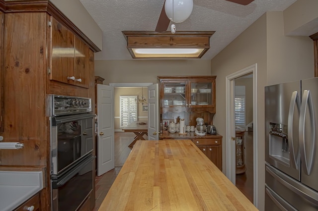 kitchen with wooden counters, stainless steel fridge, a textured ceiling, double oven, and hardwood / wood-style flooring