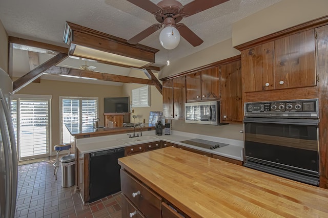 kitchen featuring kitchen peninsula, a textured ceiling, ceiling fan, sink, and black appliances