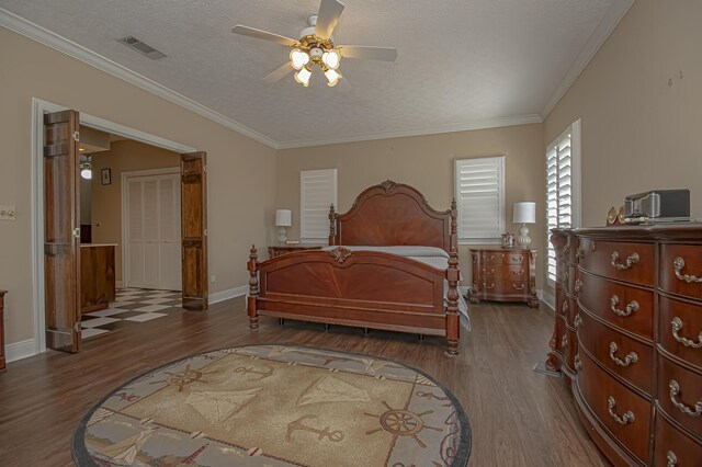 bedroom featuring ceiling fan, dark hardwood / wood-style floors, ornamental molding, and a textured ceiling